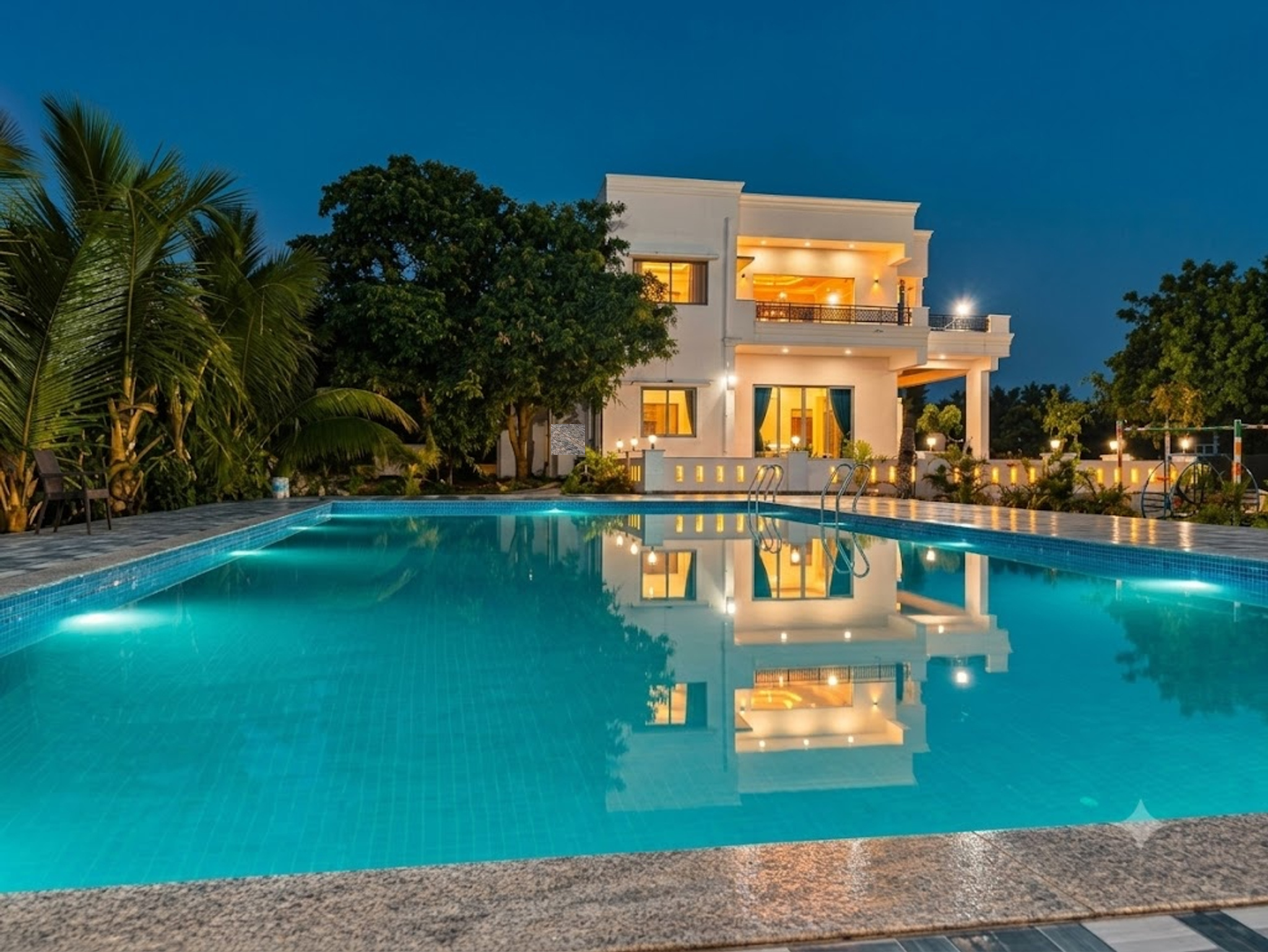 Green Enclaves Farm & Resort luxury contemporary white villa with illuminated pool at dusk